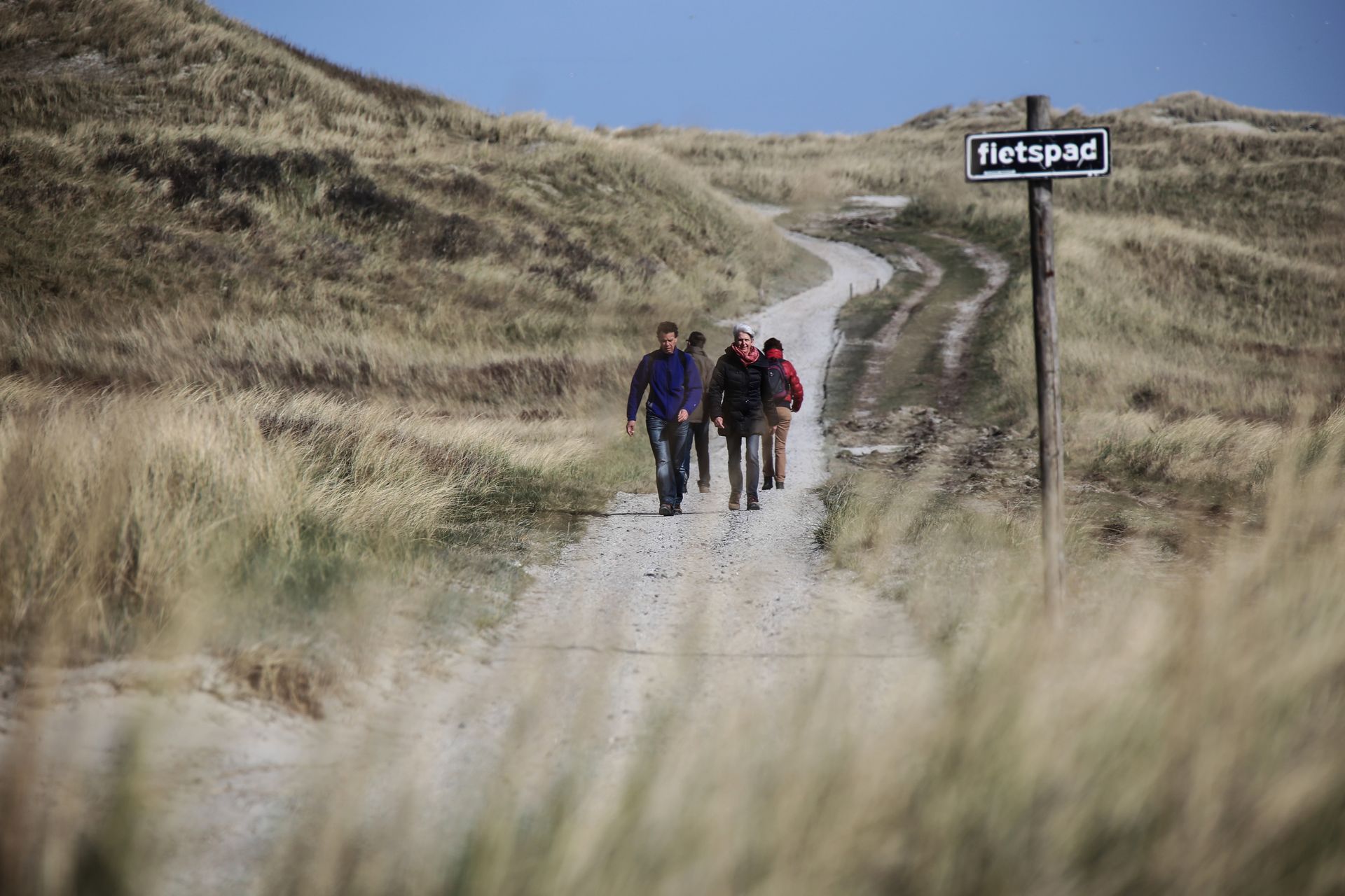 Een groep mensen loopt over een onverharde weg.