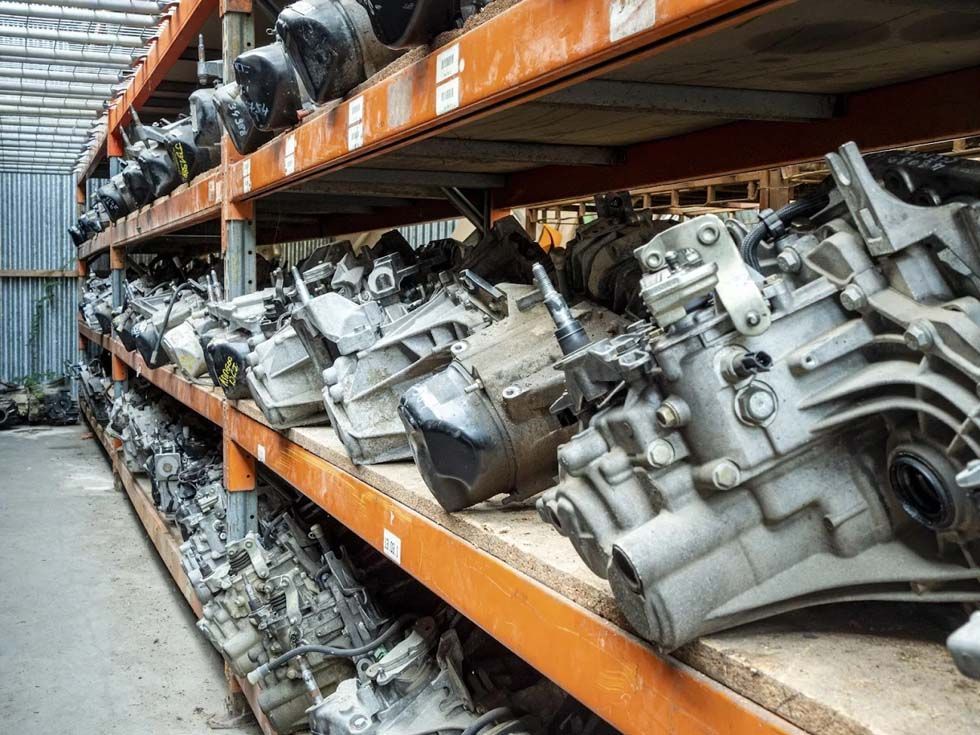 Des rangées de pièces automobiles métalliques empilées sur des étagères orange dans une zone de stockage industrielle