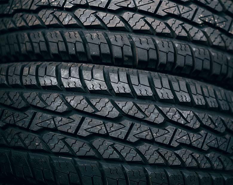 Gros plan sur des pneus de voiture noirs empilés, présentant des sculptures profondes.