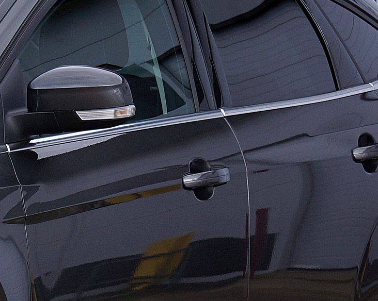 Gros plan sur les portières latérales et le rétroviseur d'une voiture noire, montrant les vitres réfléchissantes et les poignées.