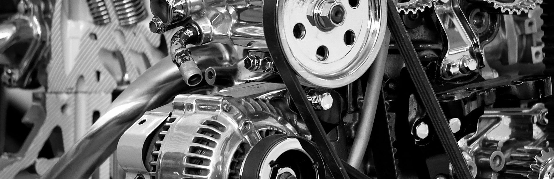 Gros plan sur un moteur de voiture avec ses composants chromés, ses courroies et ses poulies.