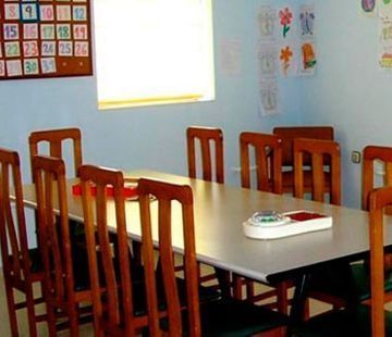 Una mesa y sillas en una habitación con un calendario en la pared.