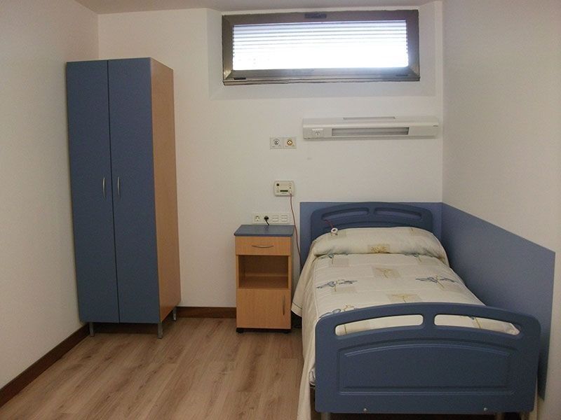 Una habitación de hospital con una cama individual y una mesita de noche.