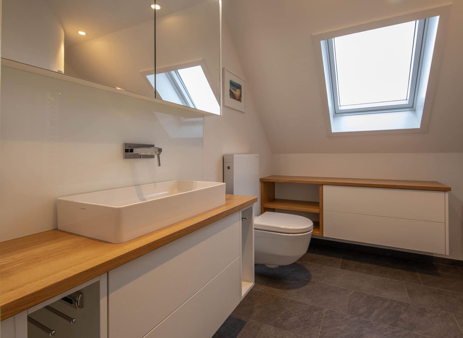 Modernes Badezimmer mit weissem Waschtisch, Holzarbeitsplatten, Toilette und Dachfenstern
