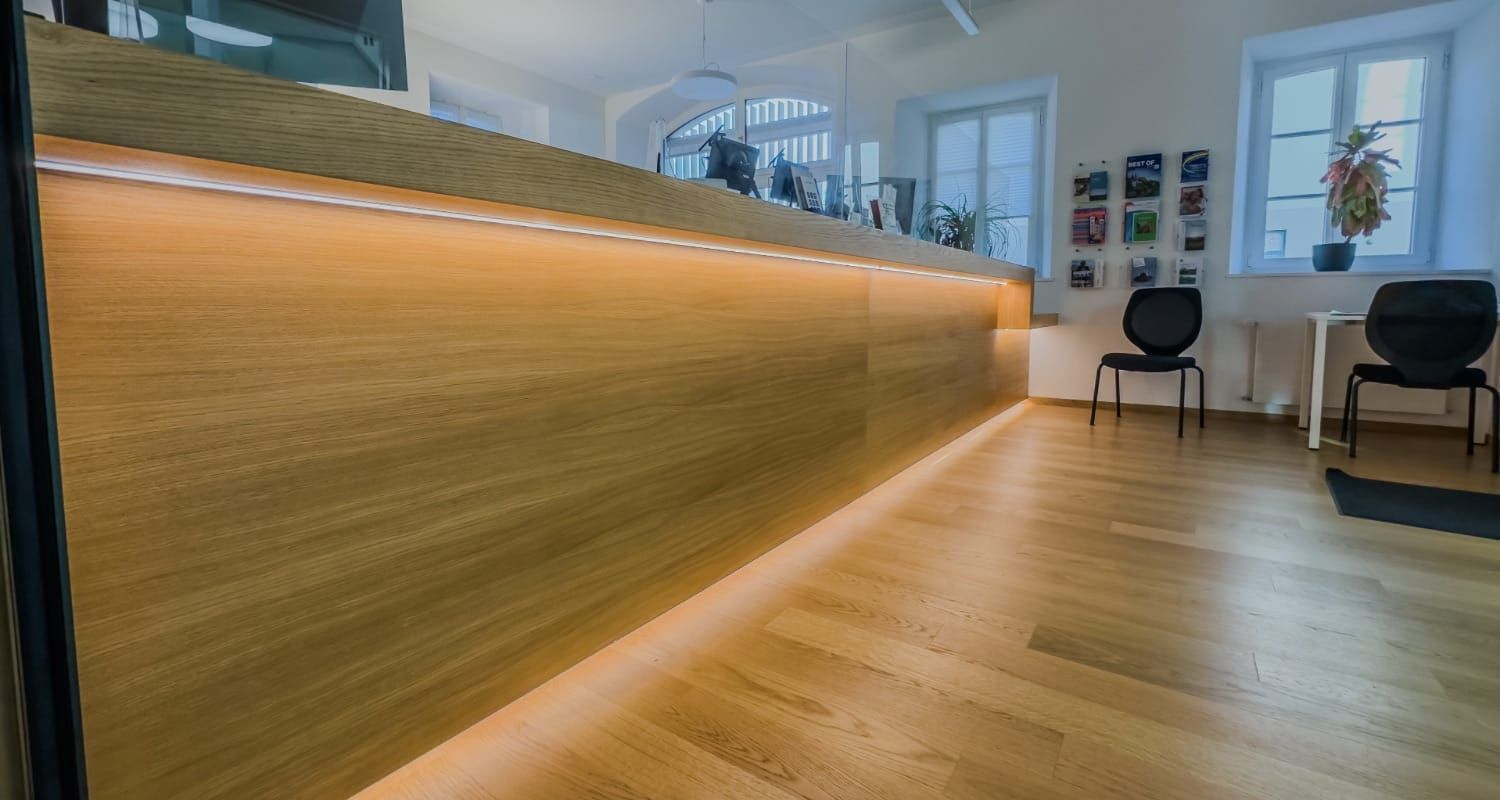 Moderner Empfangsbereich mit Holzboden in einer hellen Bürolobby
