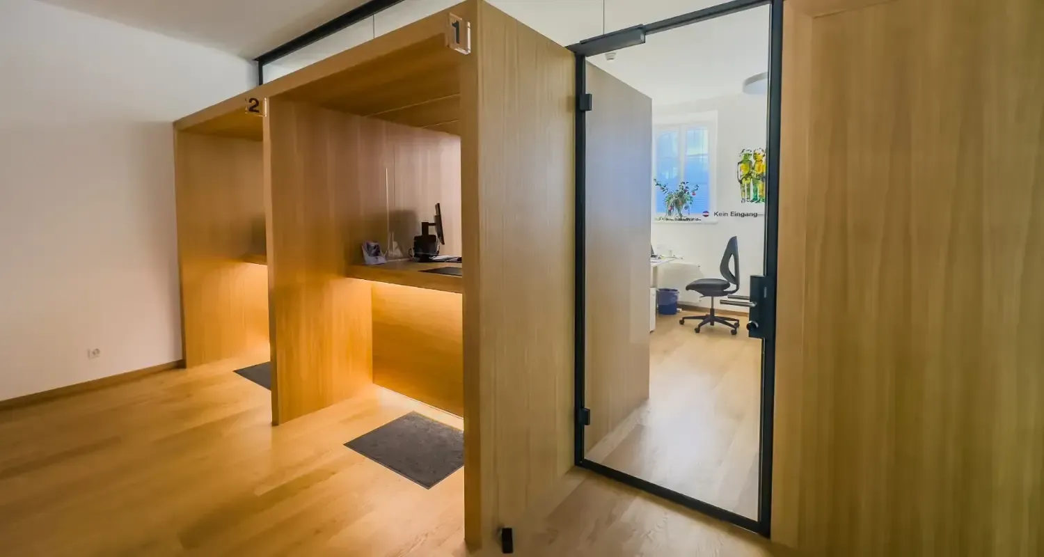 Moderner, holzgetäfelter Flur mit eingebauter Schreibtischnische und einem Spiegel, der einen kleinen Bürobereich reflektiert.