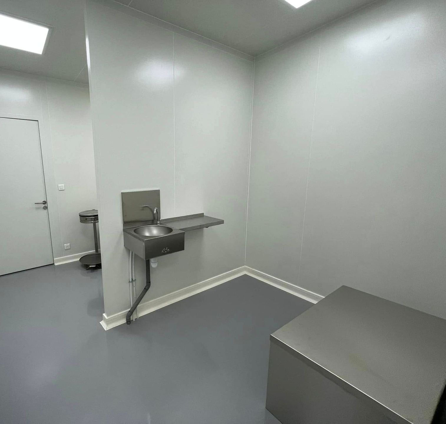 Une pièce dans un laboratoire d'usine avec un lavabo en inox et un sol vinyle gris