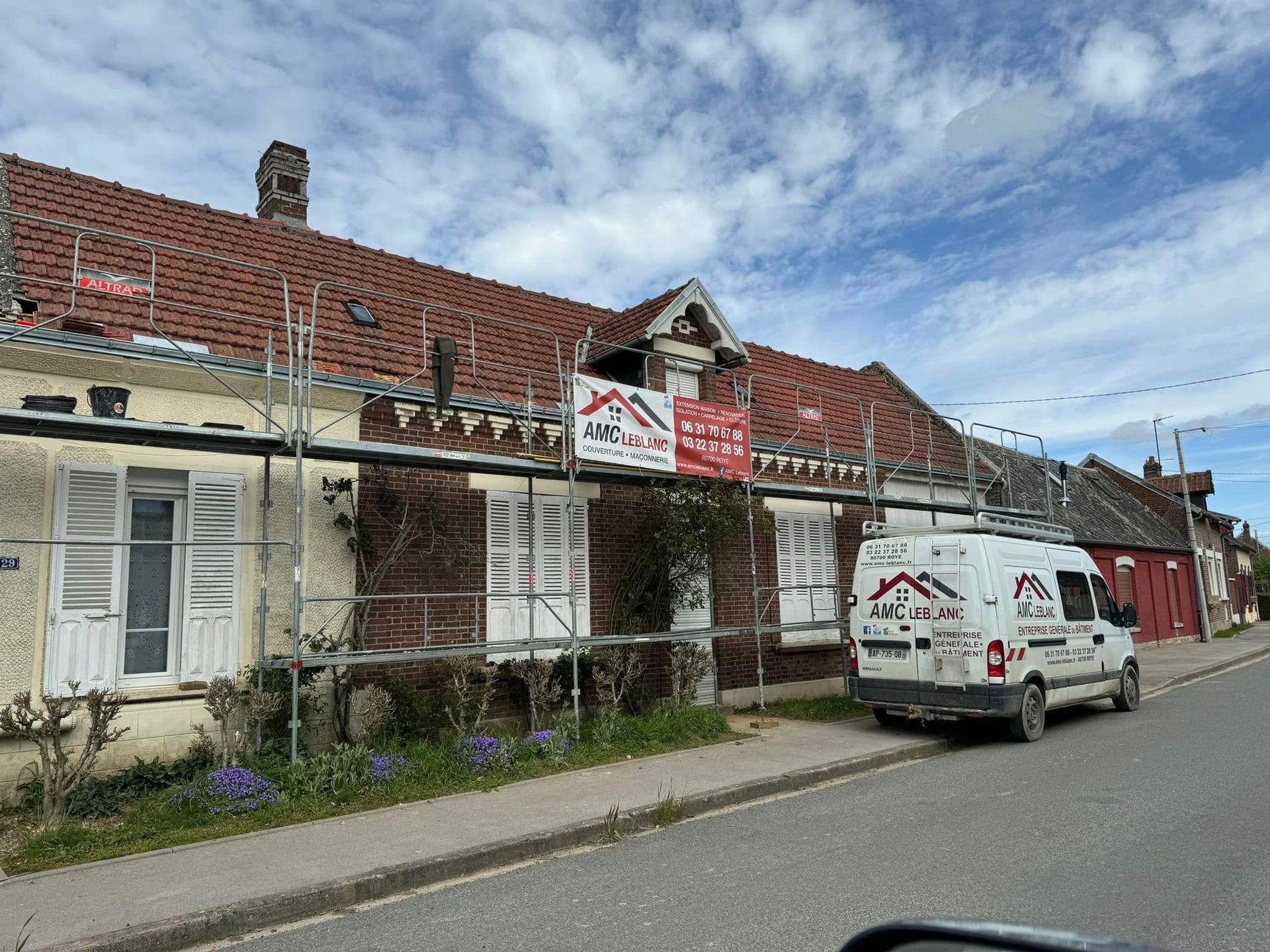 Une façade en cours de rénovation avec un échafaudage et le camion de l'entreprise