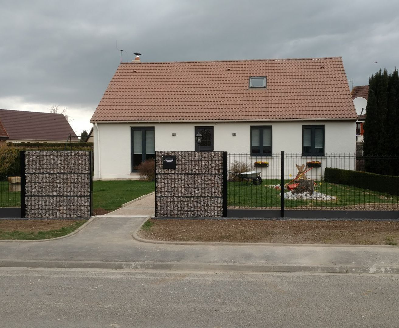 Une maison avec un muret en gabion