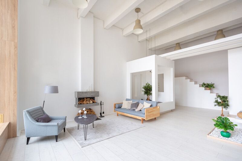 Moderna sala de estar con suelo de madera, sillas negras y una mesa de centro triangular. 