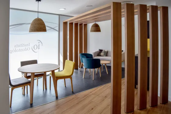 Moderna sala de espera de oficina con divisor de madera, mesas y sillas.