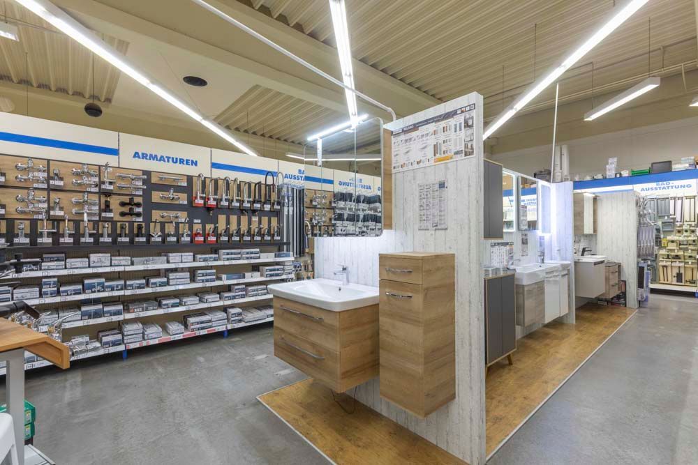 In einem Geschäft werden Badezimmerarmaturen ausgestellt, mit Waschbecken, Schränken und Beschlägen in den Regalen.