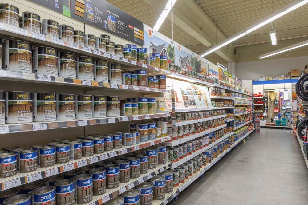 Regale mit Farbdosen in einem Baumarkt, verschiedene Farben, gut beleuchteter Gang.