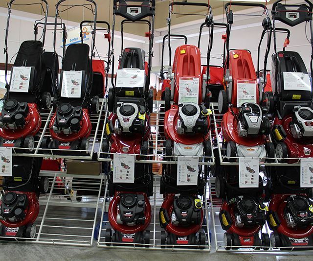 In einem Geschäft sind viele Rasenmäher ausgestellt