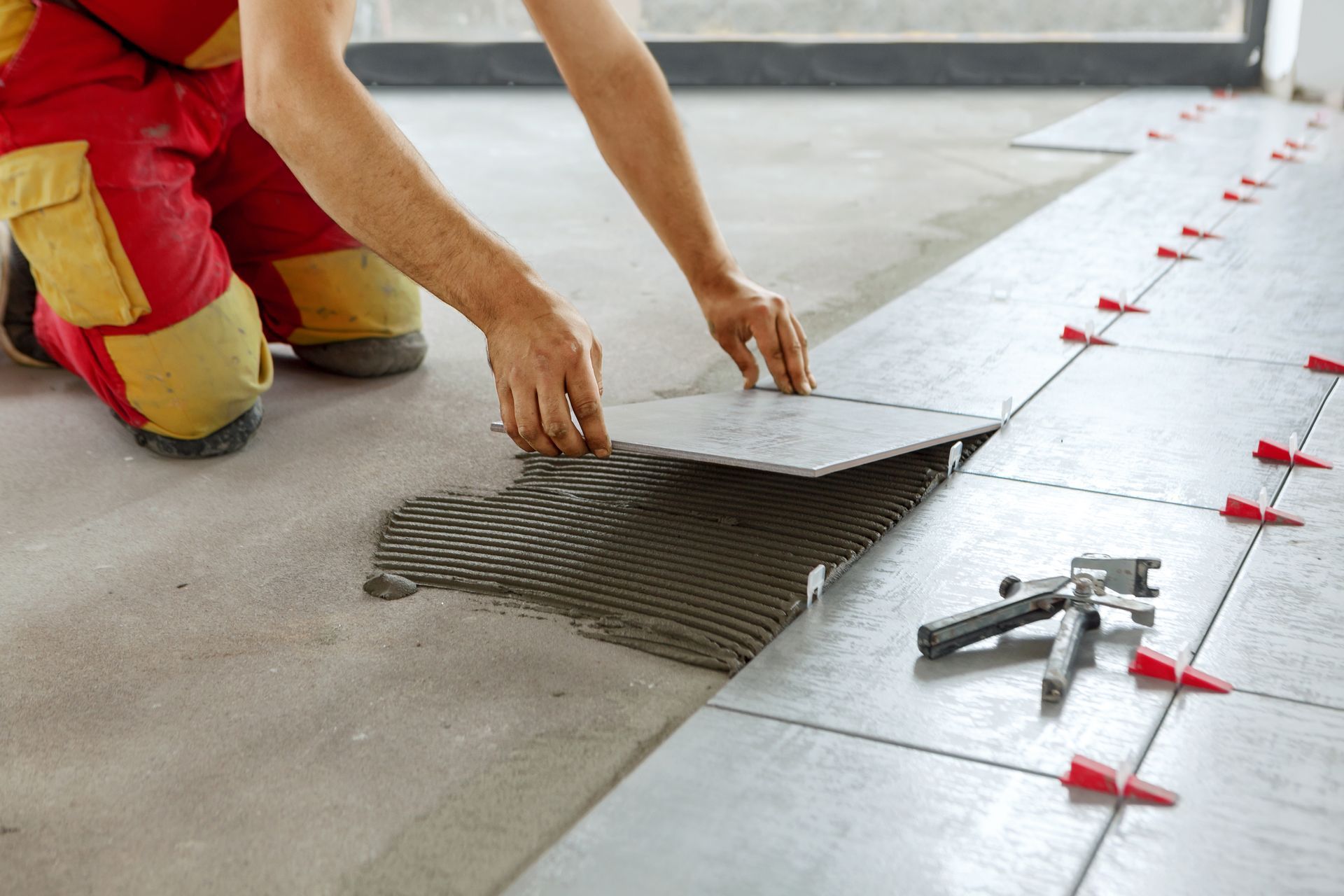 Une personne pose des carreaux sur le sol.