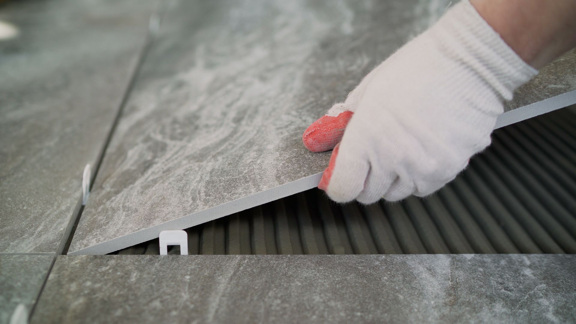 Une personne applique un produit d'étanchéité sur un sol carrelé.
