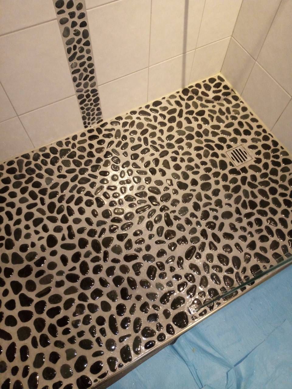 Une cabine de douche avec un sol en carrelage noir et blanc