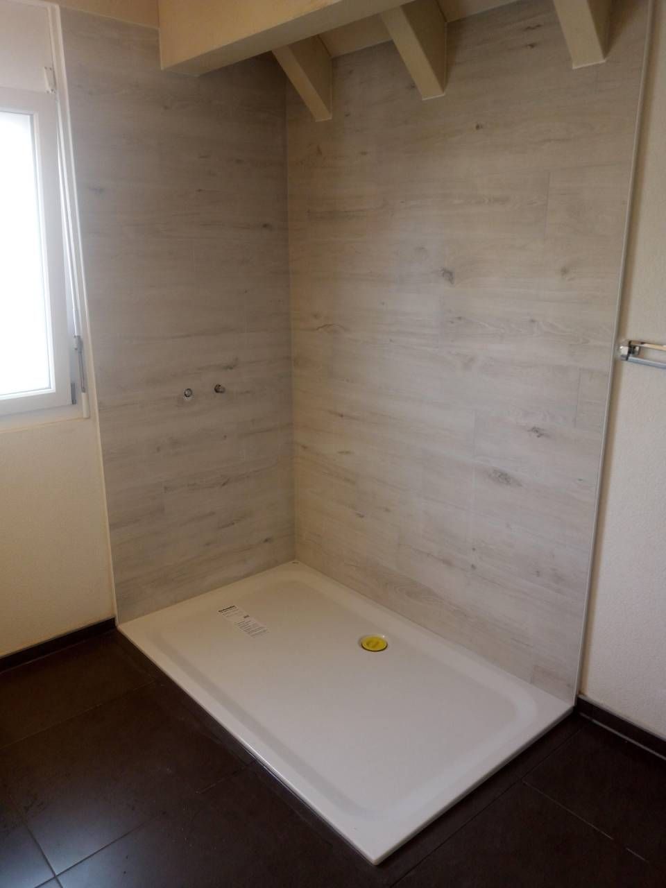 Une salle de bain avec douche à l'italienne et fenêtre.