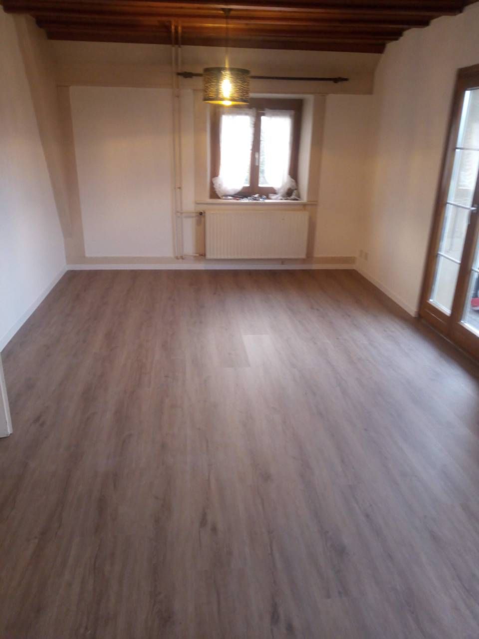 Une pièce vide avec un plancher en bois et une fenêtre.