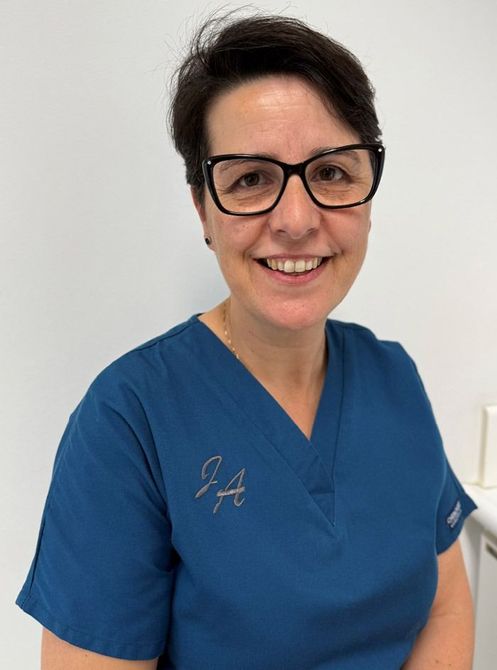 Una mujer que lleva gafas y una camiseta azul sonríe para la cámara.