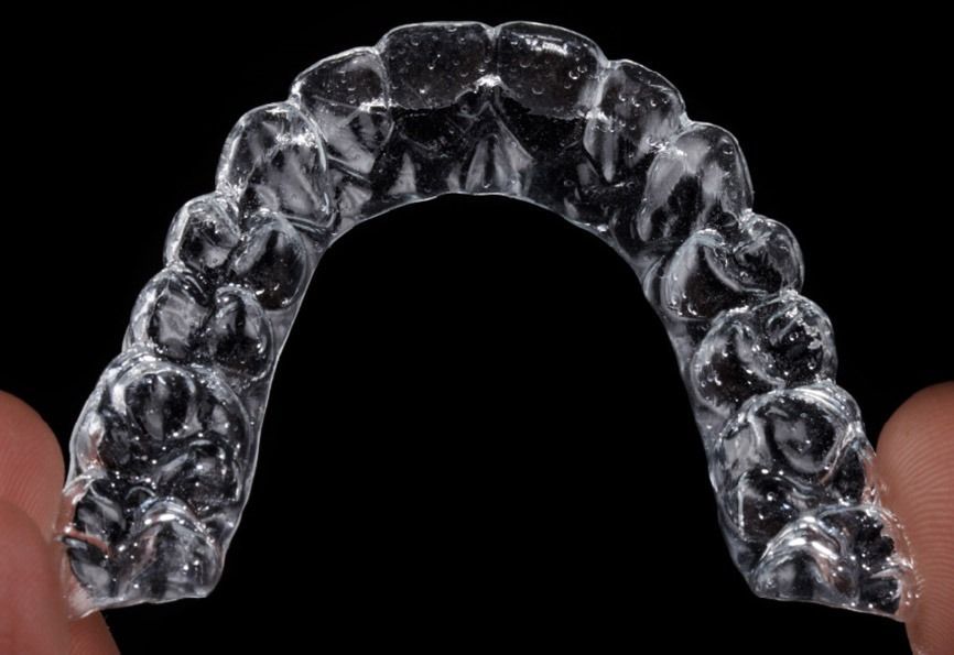Una persona sostiene un protector bucal transparente en sus manos.