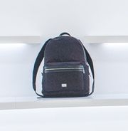 Mochila preta em uma prateleira branca, com design minimalista.