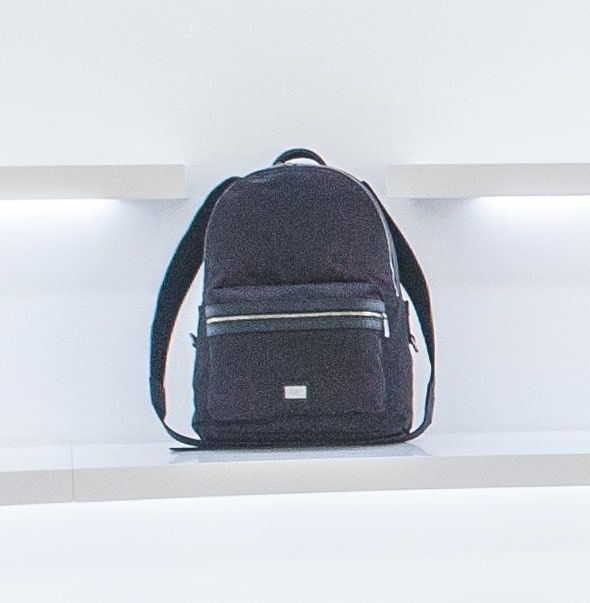 Mochila preta em uma prateleira branca, com design minimalista.