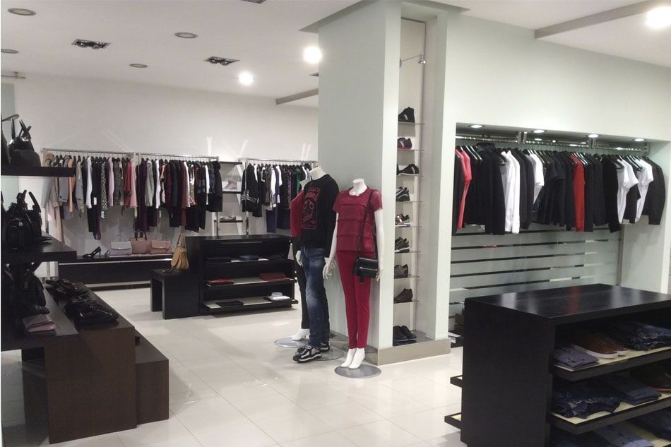 Interior de loja de roupas com manequins e prateleiras de roupas; várias cores e estilos.