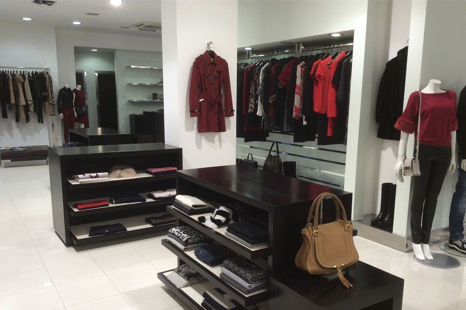 Interior de loja de roupas com araras, prateleiras e manequins.