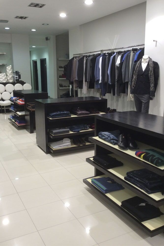 Interior de loja de roupas masculinas com prateleiras pretas, araras e um manequim.