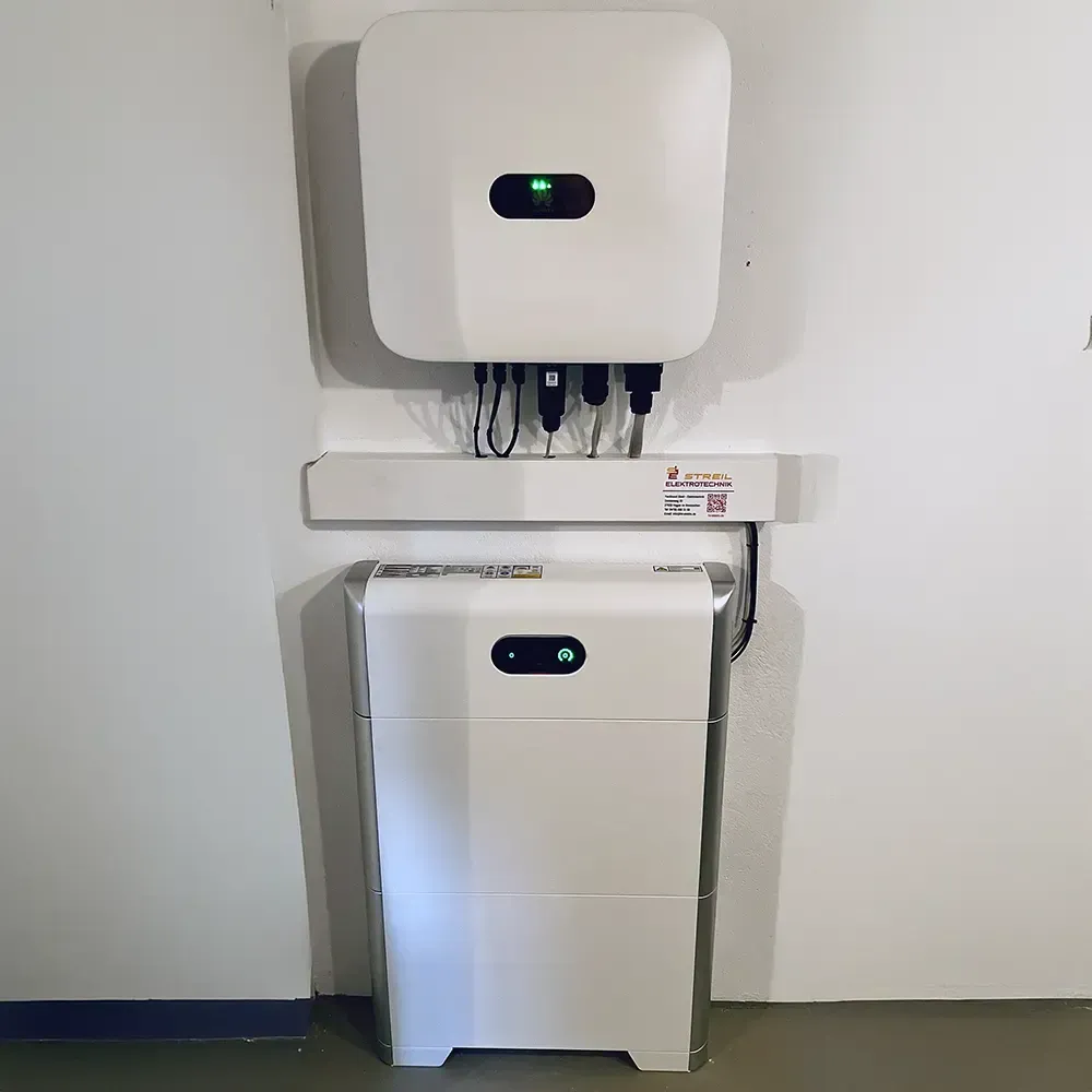 Solarwechselrichter und Batteriesystem an einer weißen Wand montiert, Kabel und Anschlüsse sichtbar.