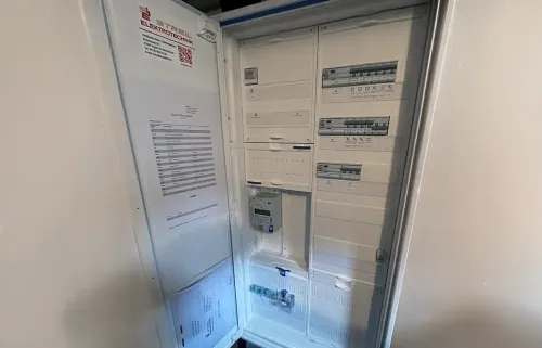 Offener Schaltschrank mit Leistungsschaltern, Dokumenten und einem Messgerät.