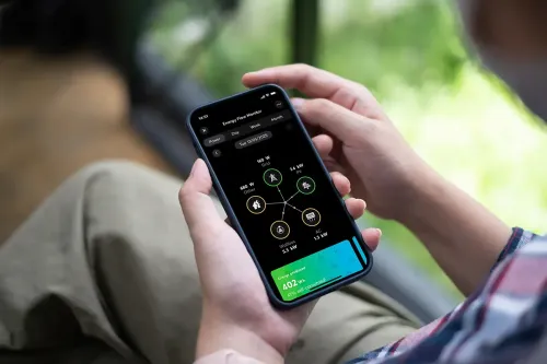 Person in einem Auto, die ein Telefon hält, auf dem eine App mit Datenvisualisierungen auf dunklem Hintergrund angezeigt wird.
