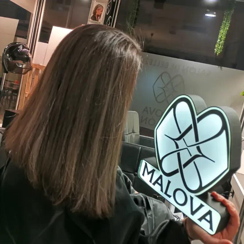 Persona con cabello largo y oscuro sosteniendo un letrero blanco brillante con la palabra 