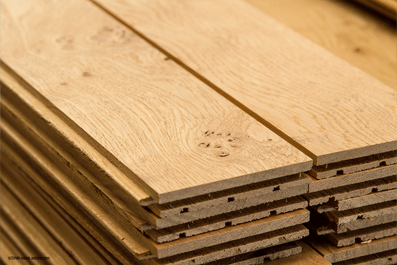 Stapel heller Holzdielen, auf denen die Maserung und die Nut-und-Feder-Verbindungen sichtbar sind.