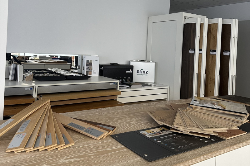 Bodenmuster und Ausstellungsstücke in einem Showroom-Ambiente, die verschiedene Holz- und Fliesenoptionen präsentieren.