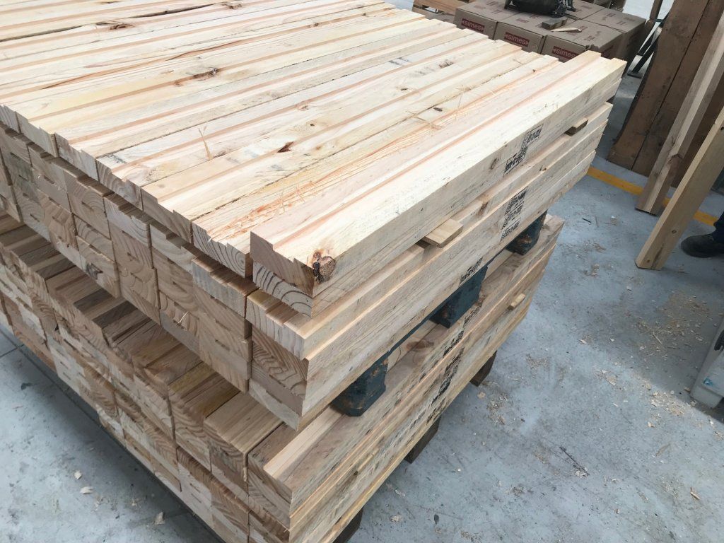Pilas de tablas de madera recién cortadas sobre un palé, posiblemente madera para construcción.