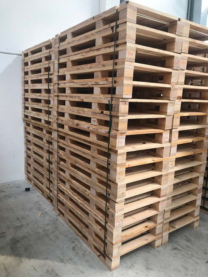 Pila de palets de madera en un entorno interior; construcción rectangular de color beige.