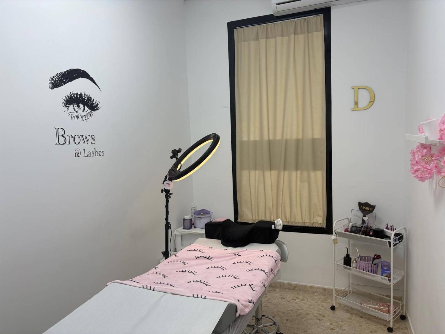 Una sala de tratamientos de belleza profesional que cuenta con una camilla de masaje con sábanas.