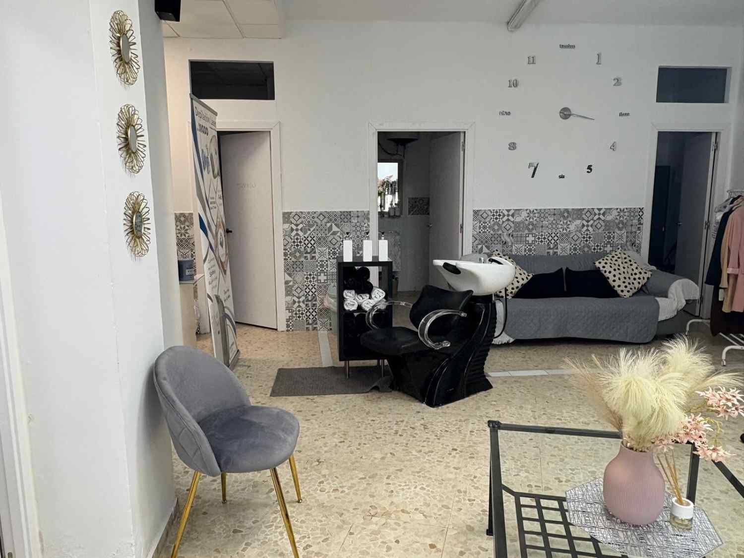 Una luminosa y moderna sala de espera de peluquería con una silla de terciopelo gris.