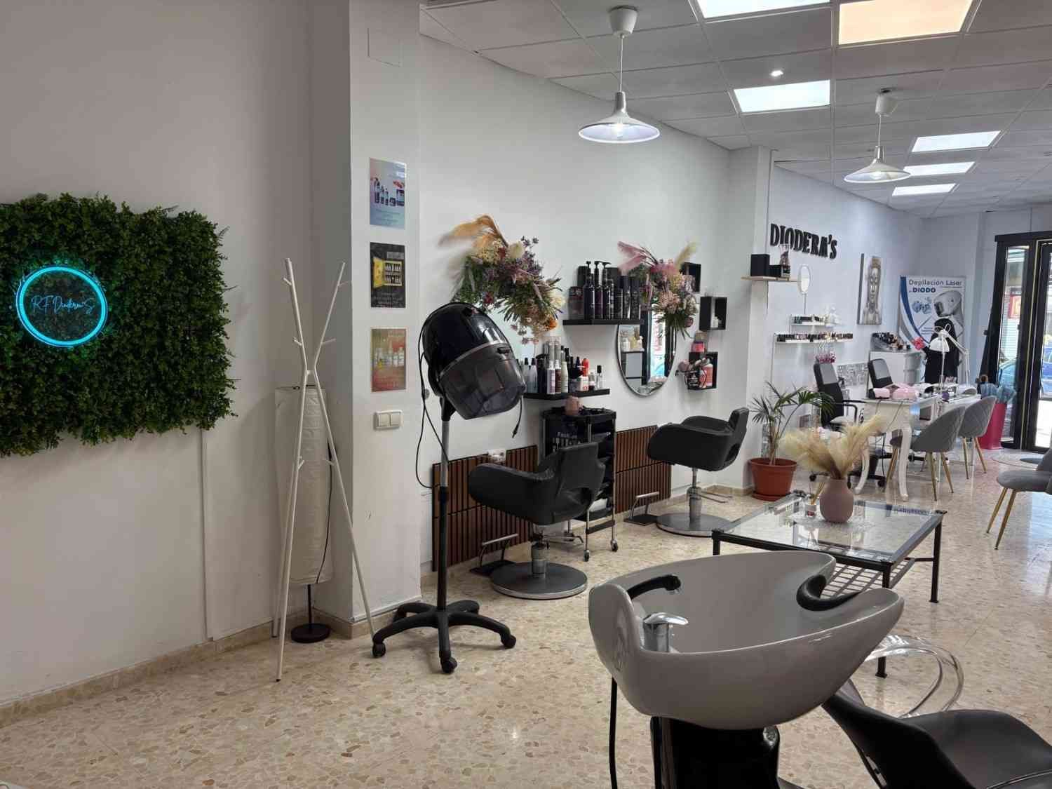 Interior de una peluquería con una zona de lavado en primer plano, sillones de peluquería.