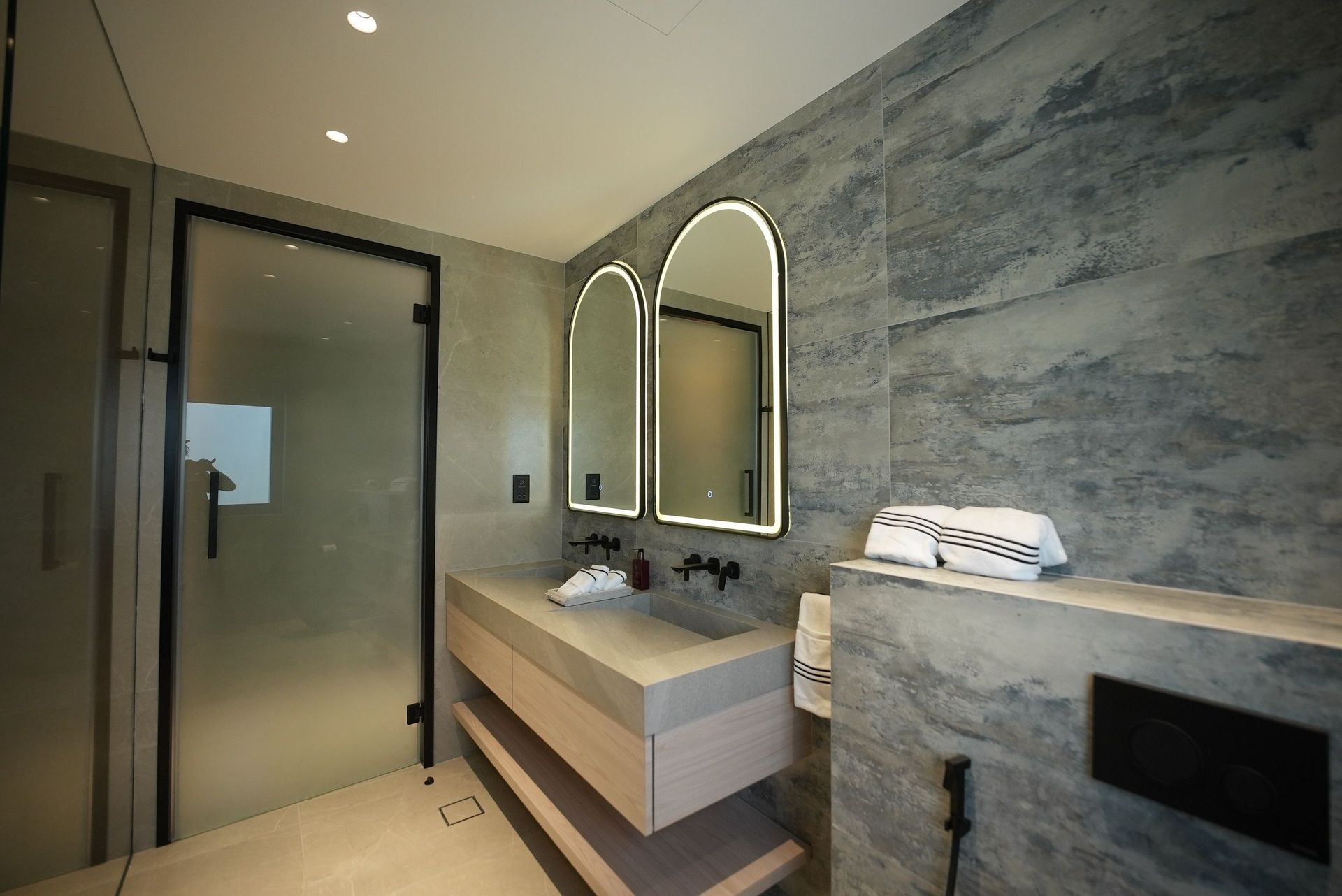 Modernes Badezimmer mit Glasdusche, Doppelwaschbecken und Marmorwandfliesen