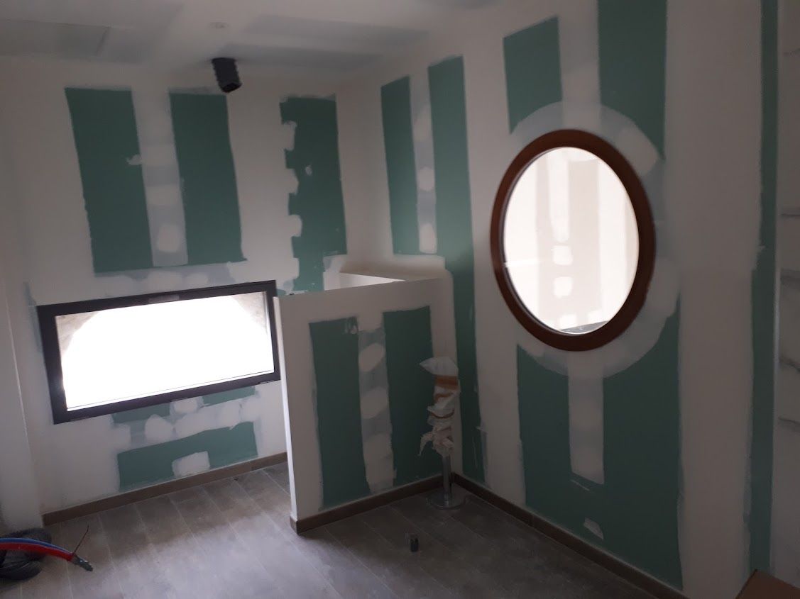 Travaux de cloisons autour d'une fenêtre ronde