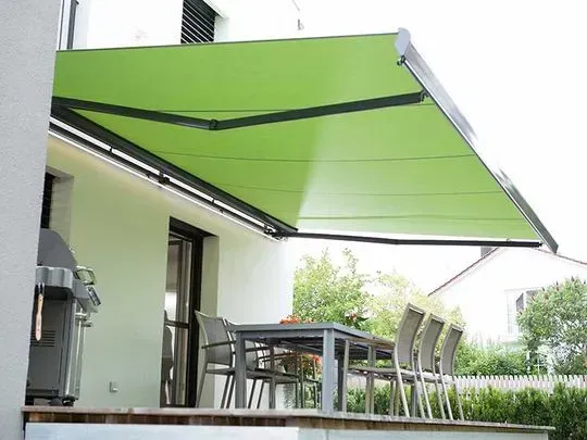 Eine grüne Markise an einem weißen Haus