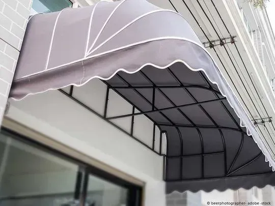 Eine gewölbte graue Markise über einer Glastür