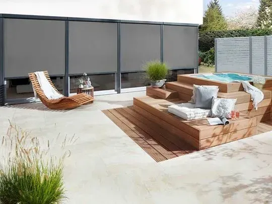 Haus mit bodentiefen Fenstern an einer Terrasse und Rolläden