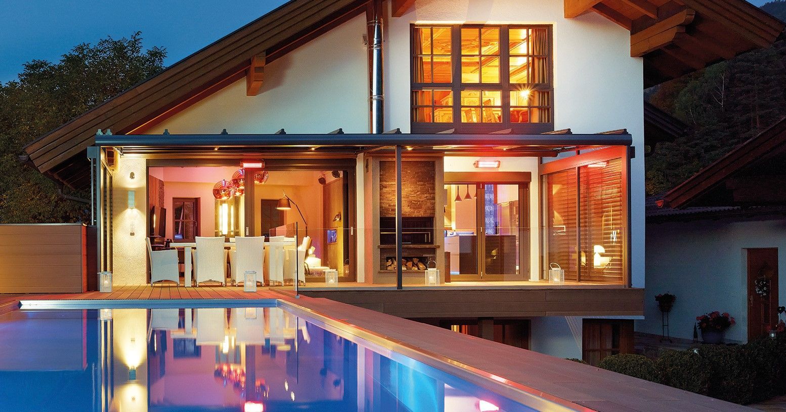 Wintergarten mit offener Glastür vor einem Außenpool