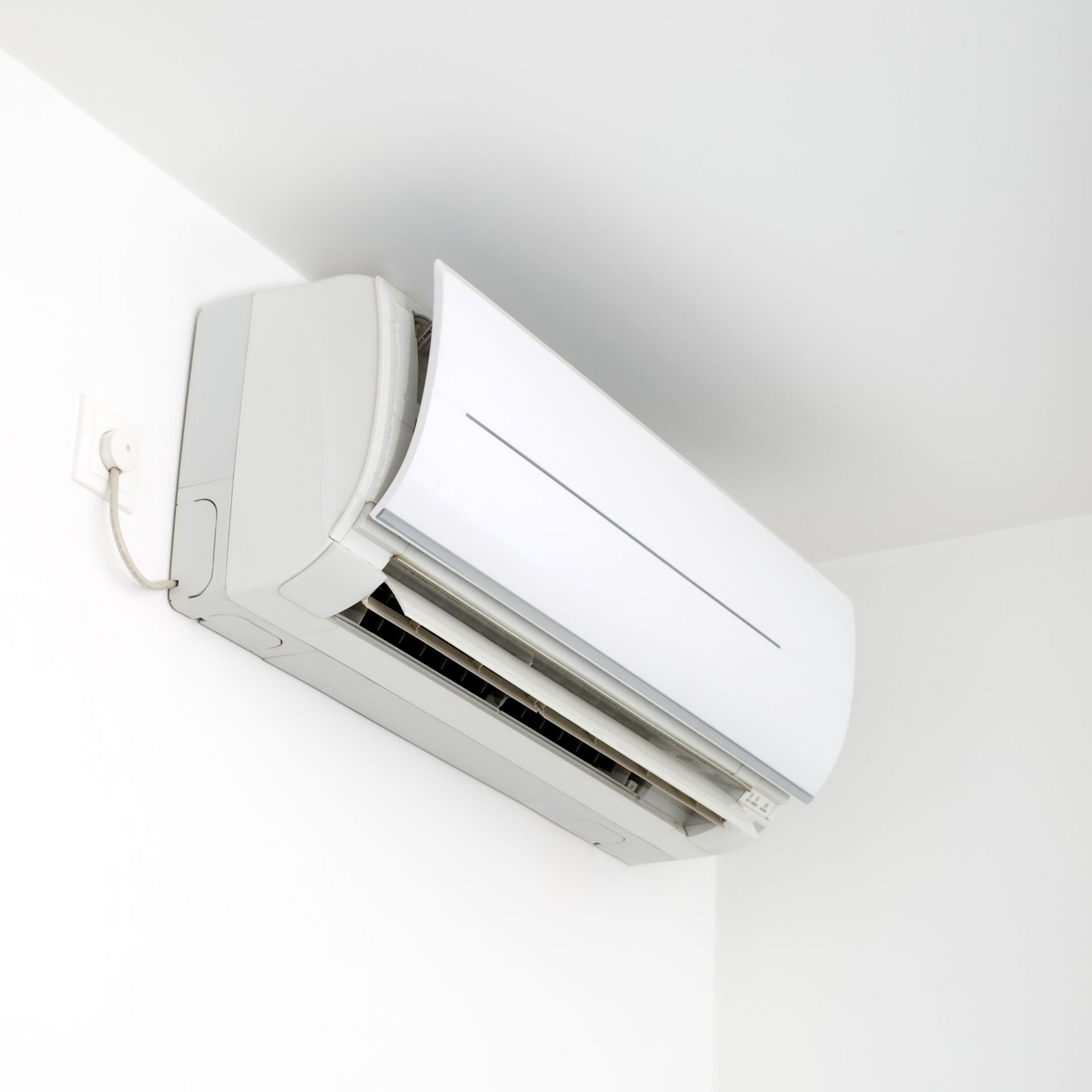 Un climatiseur extérieur équipé de deux ventilateurs superposés se trouve à côté d'une petite plante en pot, près d'un portail en métal blanc.