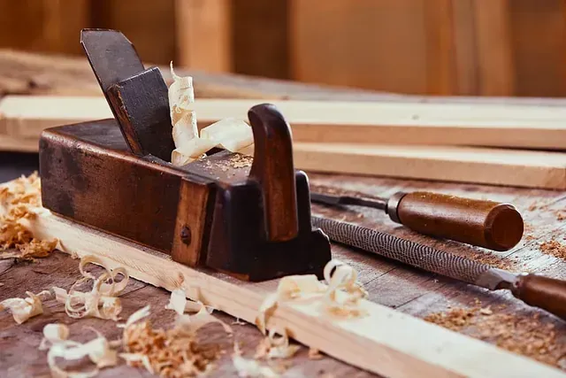 Un avión de madera está sentado encima de un trozo de madera sobre una mesa de madera.