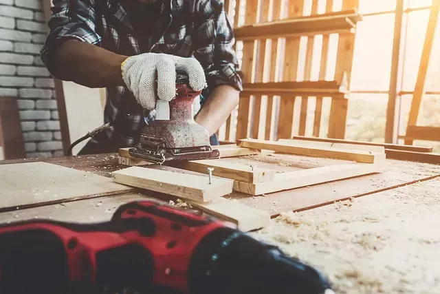 Un hombre está lijando un trozo de madera con una lijadora.